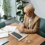 Femme professionnelle dans un bureau travaillant sur un ordinateur portable, entourée d'articles de bureau.