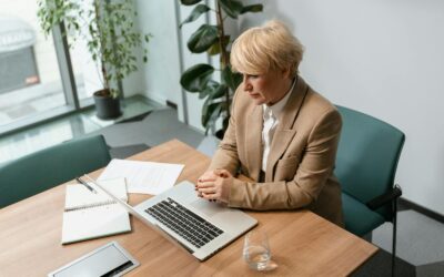 Femme professionnelle dans un bureau travaillant sur un ordinateur portable, entourée d'articles de bureau.