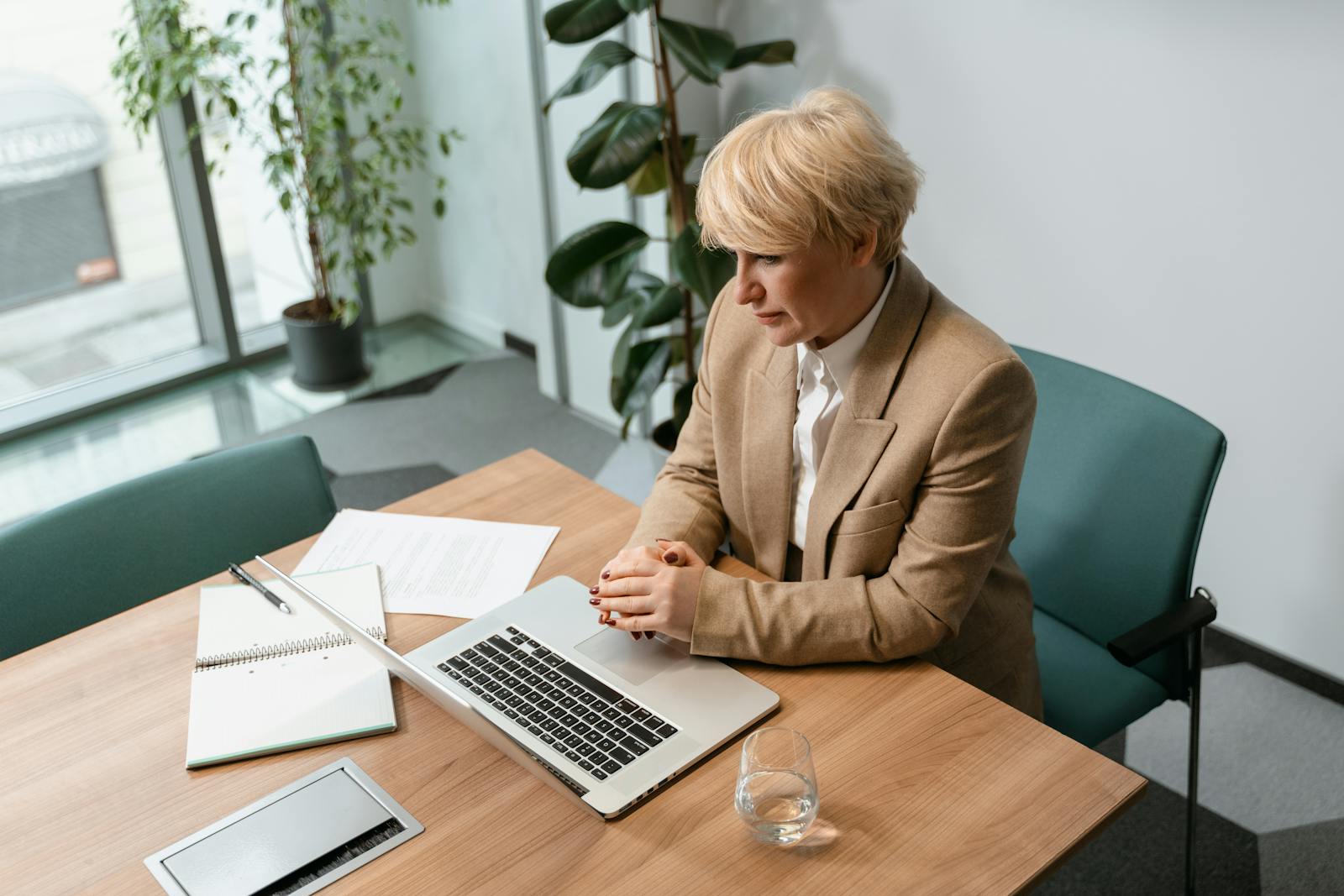 Femme professionnelle dans un bureau travaillant sur un ordinateur portable, entourée d'articles de bureau.