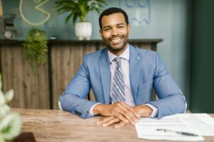 Homme d'affaires souriant en tenue de bureau assis à un bureau avec des documents.